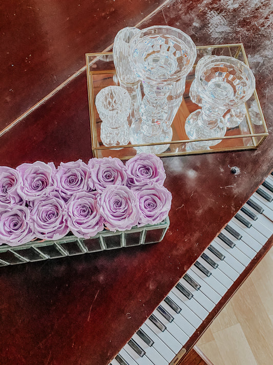 Twelve purple preserved roses on a piano with crystal. 